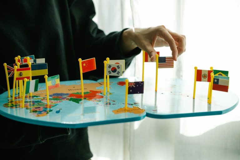 Programas de Lula e Flávio Bolsonaro divergem sobre o rumo internacional do Brasil Mão posiciona bandeiras de diferentes países sobre um mapa-múndi, em representação das relações internacionais.