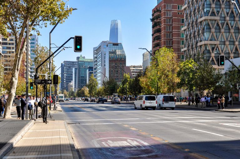 Mercado de trabalho do Chile registra desocupação de 9,6% até agosto Pessoas atravessam uma movimentada avenida de Santiago, cercadas por edifícios modernos.